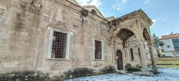 Tarihi Aya Ishotya Kilisesi'nin dış cephesi, taş duvarlar ve modern binalarla çevrili.
