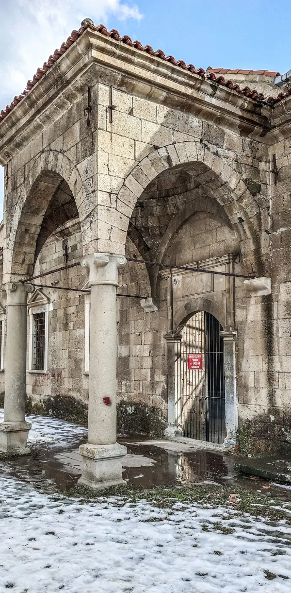 Tarihi Aya Ishotya Kilisesi'nin kış mevsiminde çekilmiş cephesi, taş sütunlar ve kiremitli çatı ile dikkat çekiyor.