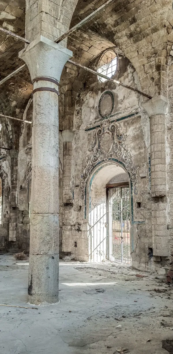Eski bir yapının iç mekanında yüksek kavisli tavan ve büyük taş sütunlar görünmekte.