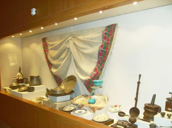 Tarihi nesnelerin sergilendiği vitrin, renkli örtü arka planda.