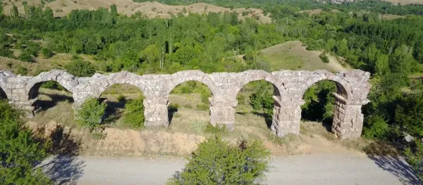 Yeşil ormanlık alanda yer alan taş yapı, yuvarlak açıklıklarıyla dikkat çekiyor.