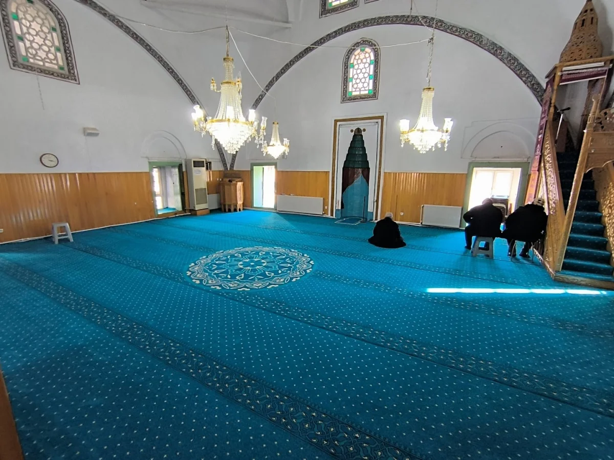 Aydınlık cami iç mekanında mavi halı, yüksek tavan ve ilginç mimari detaylar dikkat çekiyor.