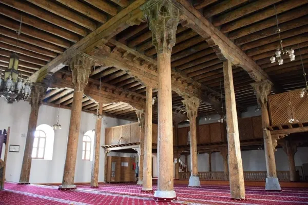 Tarihi caminin ahşap sütunları ve kırmızı halısı ile iç mekan görünümü
