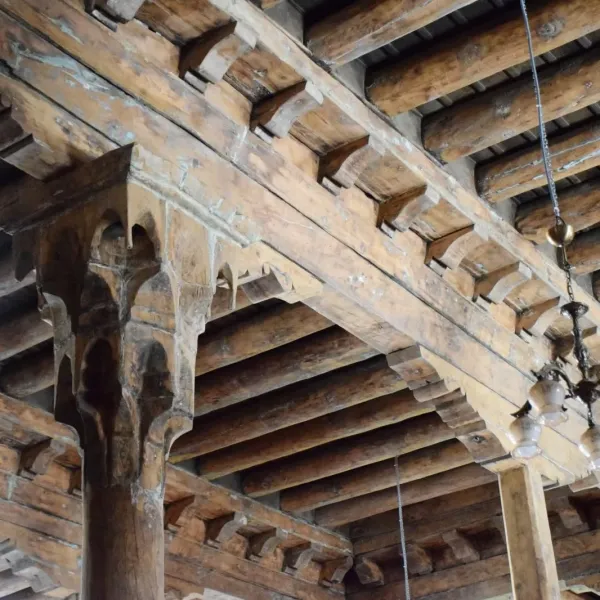 Ahşap kirişlerden yapılmış, işlemeli sütunlarla desteklenen tarihi cami tavanı
