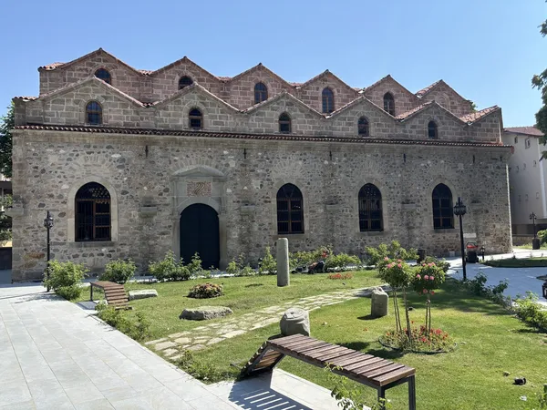 Tarihi Aya Ishotya Kilisesi, bahçe ve mavi gökyüzü ile çevrili.