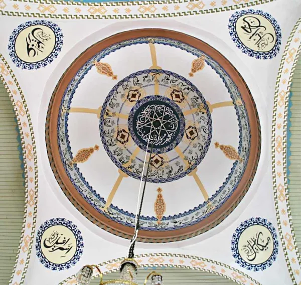 Mavi ve altın desenlerle süslü dairesel cami kubbesi iç kısmı