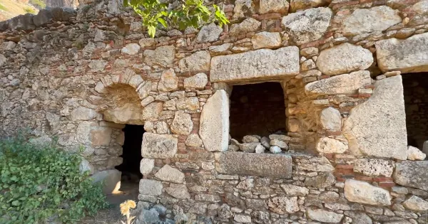 Eski taş yapının kalıntıları, kemerli kapı ve pencerelerle tarihi bir atmosfer sunuyor.