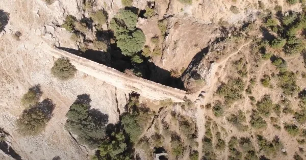 Eski bir köprü, çevresindeki doğal alanla uyum içinde ve tarihi bir atmosfer sunuyor.