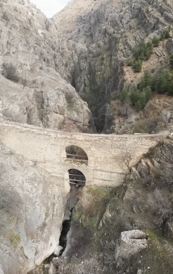 Tarihî taş köprü, yüksek kayalıklar arasında yer alıyor. Etrafı doğal manzara ile çevrili.