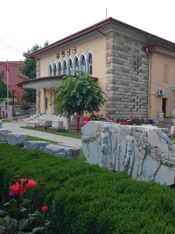 Taş duvarlı müze binası, önünde çiçekler ve bahçe ile çevrili.