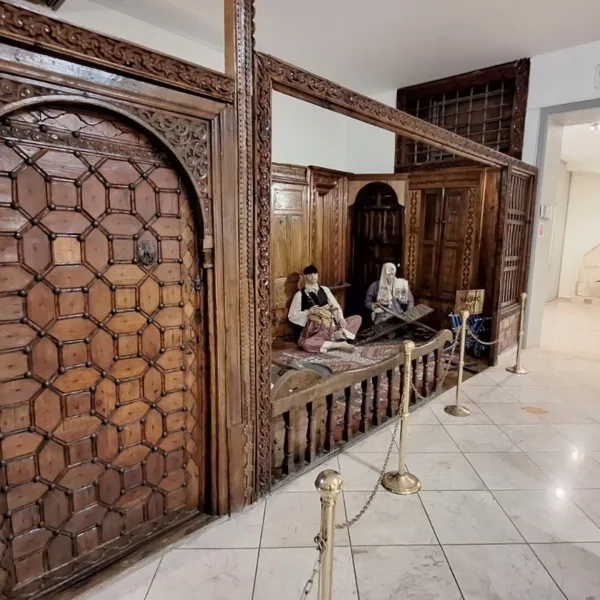 Geleneksel bir odada oturan iki heykel ve zengin oymalı ahşap yapı