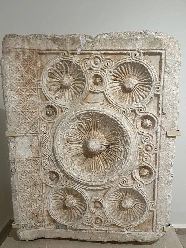 Büyük bir taş yüzeyde çiçek ve geometrik desenlerle süslenmiş kabartma tasarımı.