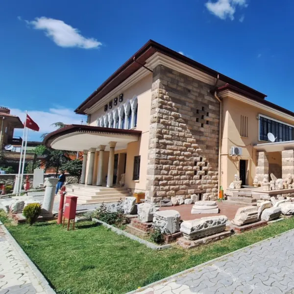 Kesme taş mimari ile inşa edilmiş tarihi müze binası, geniş bahçe ve Türk bayrağı.