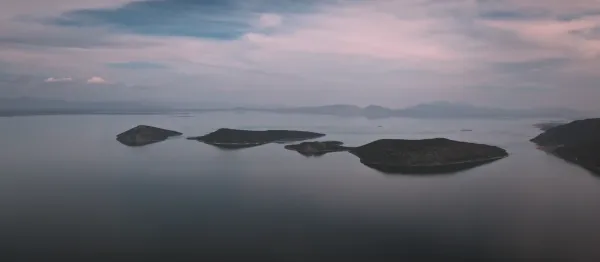 Sakin su yüzeyinde yansıyan mavi gökyüzü ve adalar.