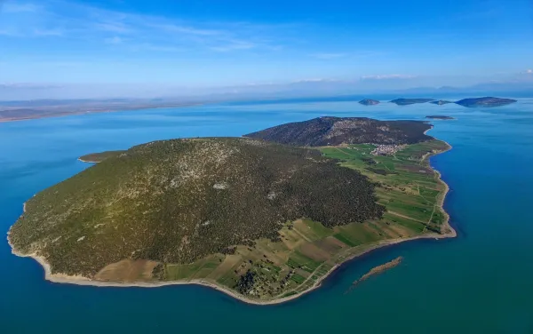 Yeşil tepe ile çevrili mavi su ve adacıklar manzarası