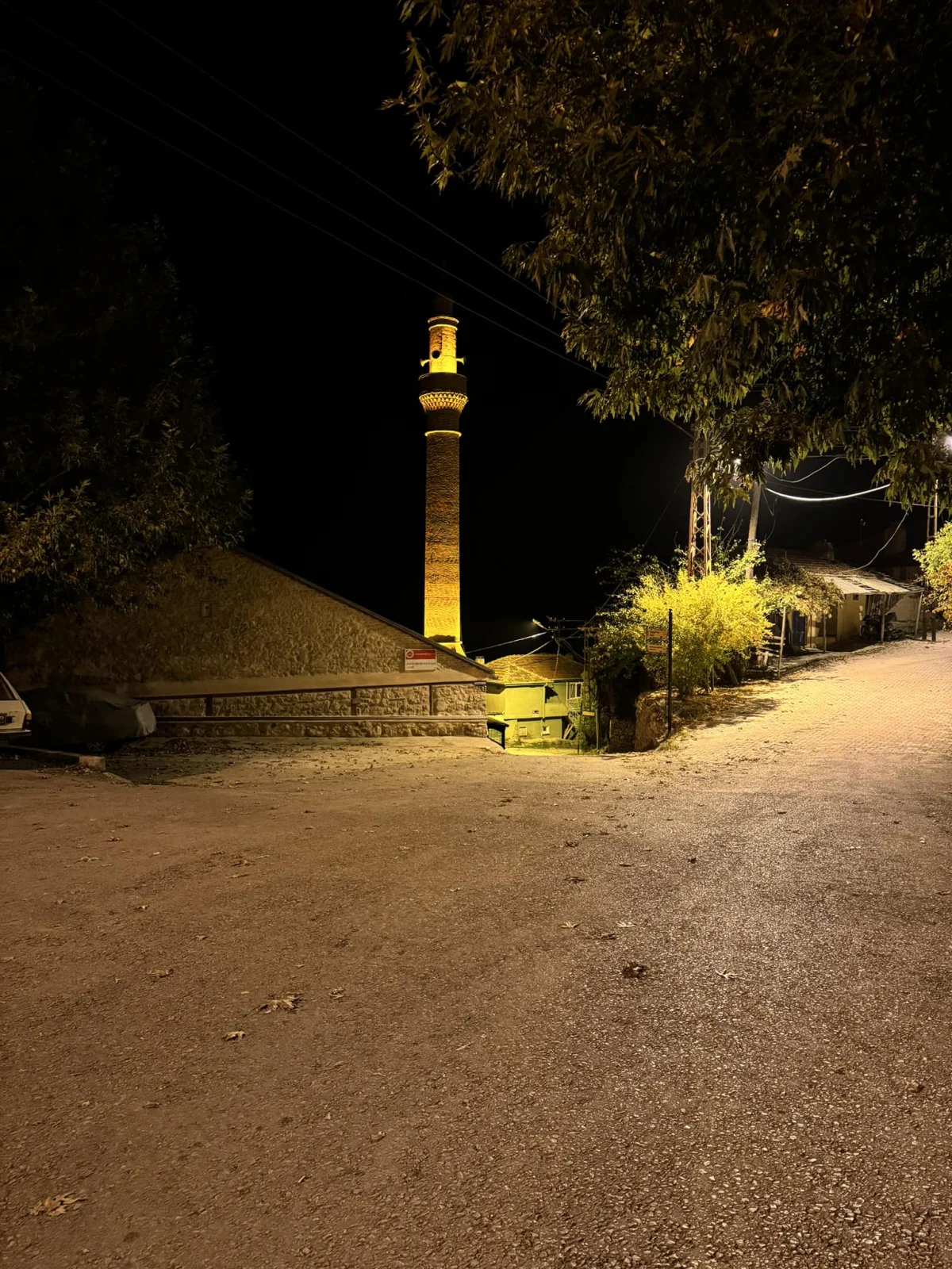 Sıcak ışıklarla aydınlatılmış Çeşnigir Paşa Camii minaresi ve taş döşeli sokak