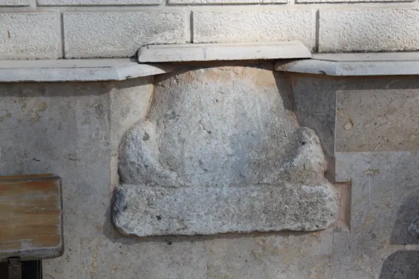 Taş yüzeyde yer alan düz yapı, eğimli taş parçası ve açık duvar arka planıyla dikkat çekiyor.