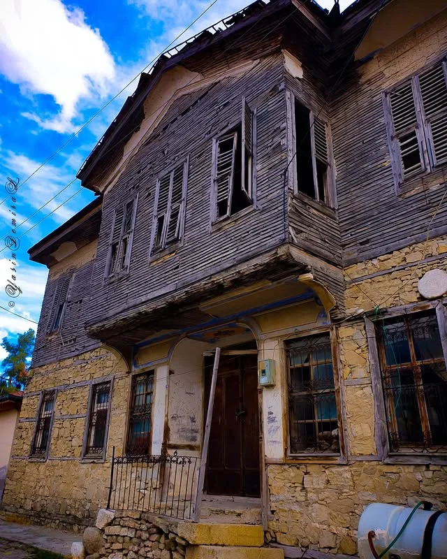 Eski bir evin dış cephesi, tahta kaplama ve taş duvarlar ile tarihi bir yapı