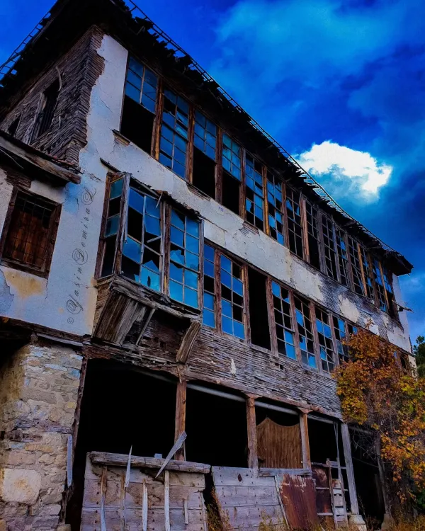 Terkedilmiş bina, büyük pencereleri ve bozulmuş ahşap yapısıyla dikkat çekiyor.