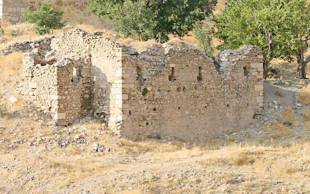 Yıkık taş yapısı, doğal alanda ağaçlar ve yeşil zemin ile çevrili