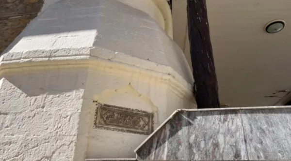 Beyaz sıvalı duvarın altındaki işlemeli taş levha ve sütun detayları