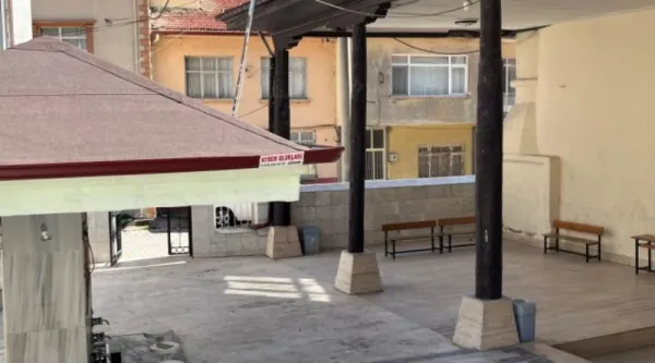 Açık alanda büyük direklerle desteklenmiş çatı ve ahşap banklar.