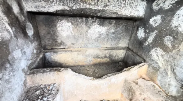 Taş yapının iç kısmında aşınmış duvarlar ve mezar alanı