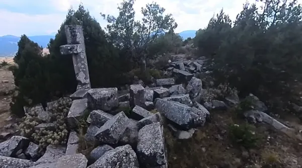 Ormanlık alanda yosun kaplı taş yığınları ve arka planda yeşil dağlar