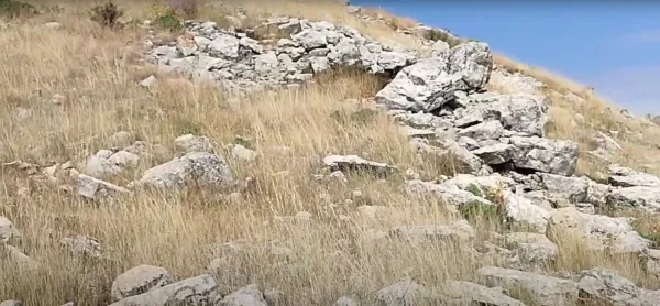 Kuru otlar ve doğal taşlarla kaplı arazide açık mavi gökyüzü