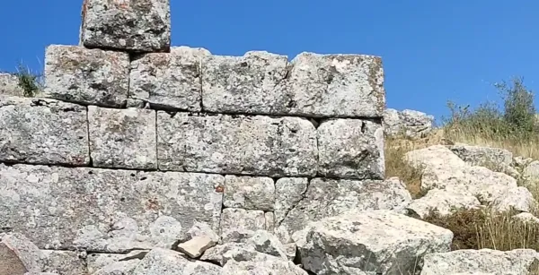 Taş duvar kalıntıları, yosunlu yüzeyler ve berrak mavi gökyüzü