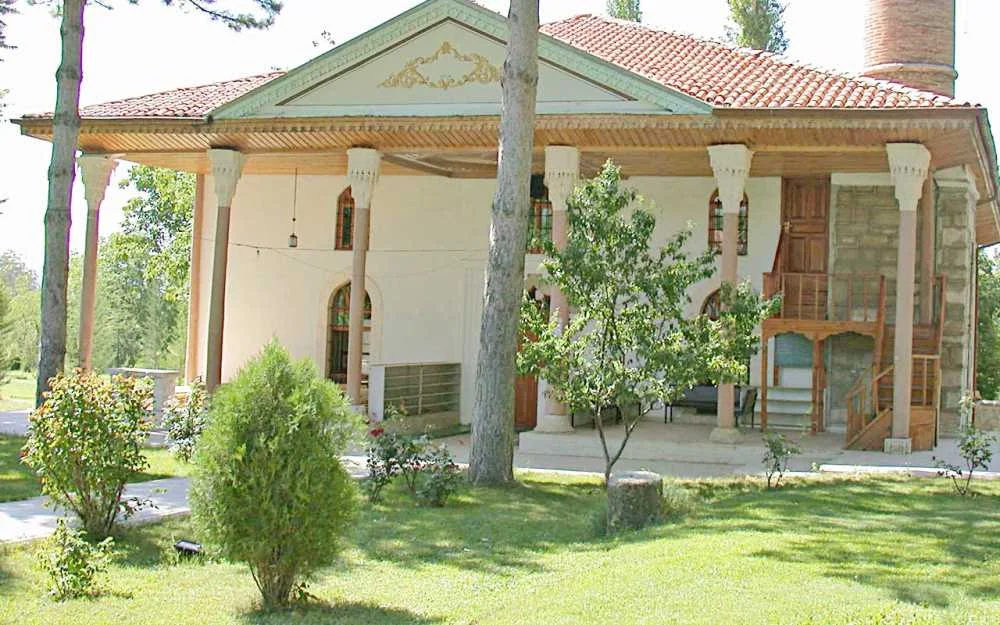 Geniş bahçede ahşap sütunlarla çevrili tarihi cami yapısı