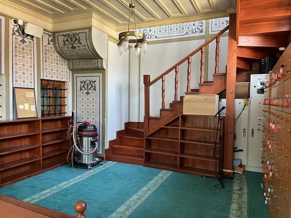 Feyzullah Paşa Camii'nin iç mekânında ahşap raflar ve geleneksel motiflerle süslenmiş duvarlar görülüyor.