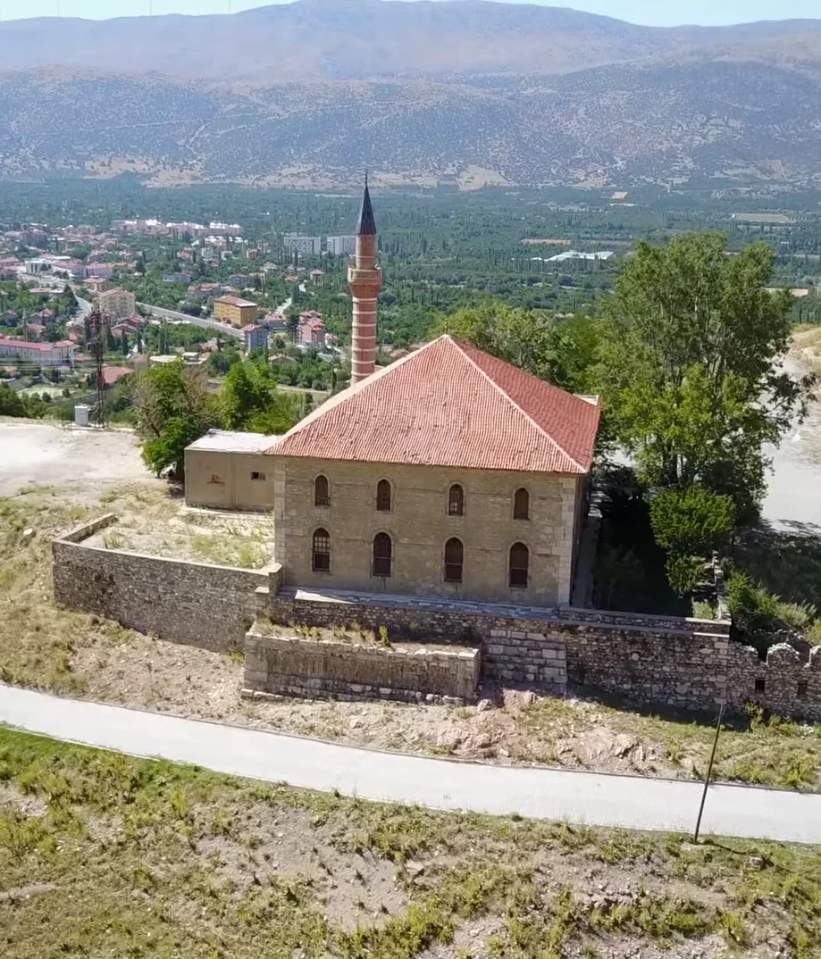 Dağların eteklerinde, kırmızı kiremitli çatısı ile Alaaddin Camii ve çevresindeki doğal alanlar.