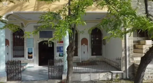 Alaaddin Camii'nin ön cephesi, yeşil ağaçlar ve taş döşeme ile çevrili.