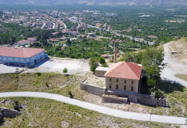 Yeşil vadideki Alaaddin Camii, kırmızı kiremitli çatısı ve ince minaresiyle göz alıyor.