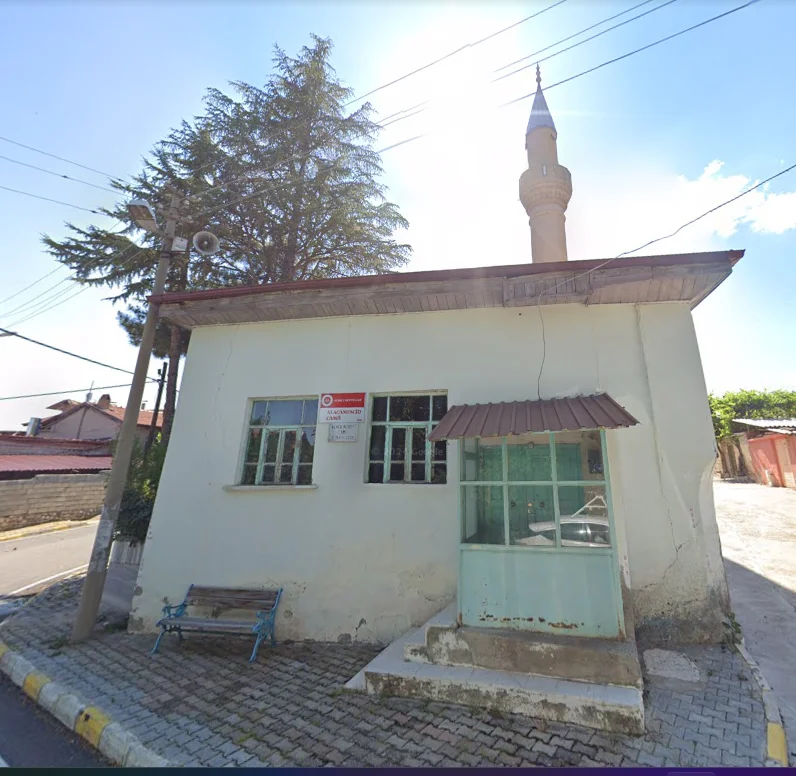 Beyaz dış cepheli Alaca Mescit Camii, ince minaresi ve çevresindeki ağaçlar ile dikkat çekiyor.