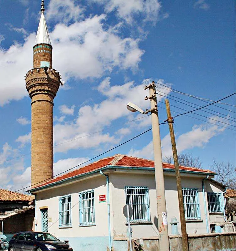 Ali Efendi Camii, geniş gökyüzü altında, mavi çerçeveli pencereleri olan bina ile birlikte görülüyor.