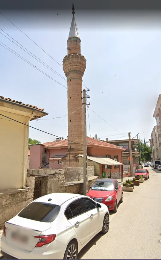 Taş yapılı tarihi minare, sivri külahı ve çevresindeki yapılarla birlikte görünüyor.