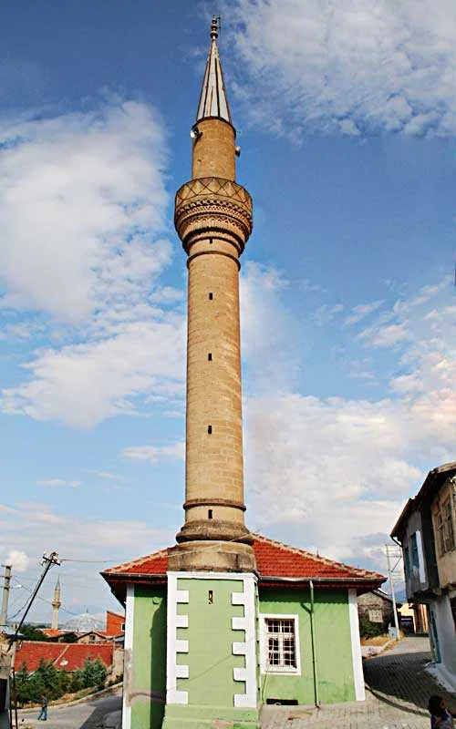 Yeşil tabanlı tarihi caminin minaresi ve arka planda mavi gökyüzü