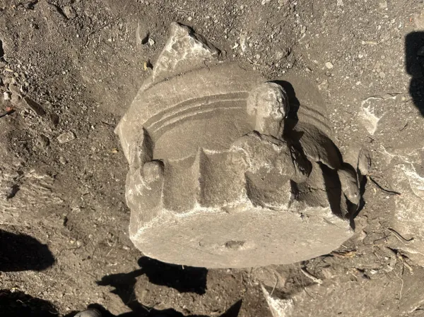 Yuvarlak kabartmalı taş eser, doğal zemin üzerinde duruyor.