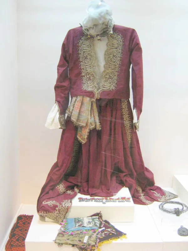 Koyu kırmızı elbise ve dantel ceket detaylarıyla geleneksel kıyafet sergisi.