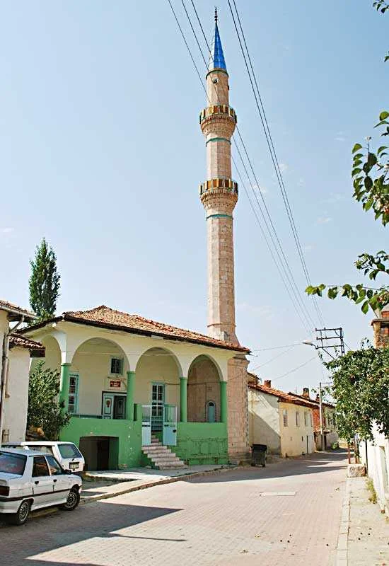 Tarihi cami, yeşil sütunlar ve ince uzun minare ile çevrelenmiş sokakta yer alıyor.