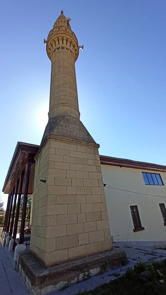 Yılanlıoğlu Camii'nin taş minaresi, gökyüzüne yükseliyor ve güneş ışığı ile parlıyor.