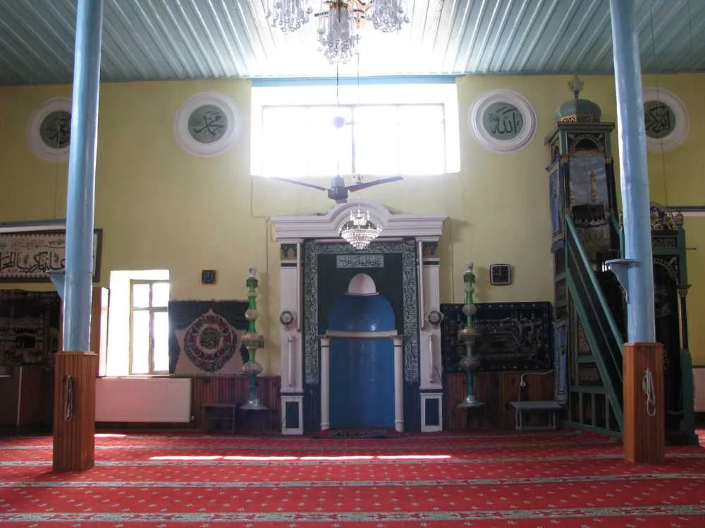Yılanlıoğlu Camii'nin iç mekanında mavi mihrap ve geleneksel halı görünümü.