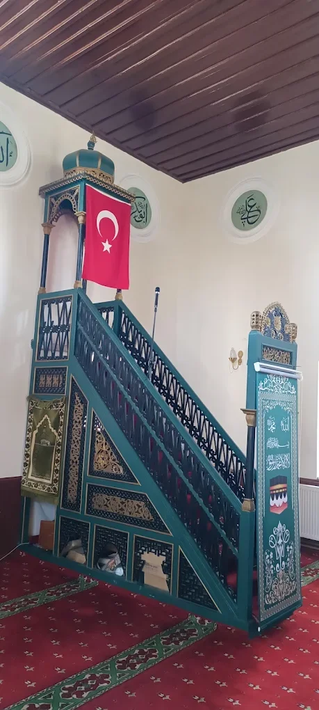 Yeşil dekoratif minber, Türk bayrağı ve Arap harfleriyle süslenmiş beyaz duvarlar.