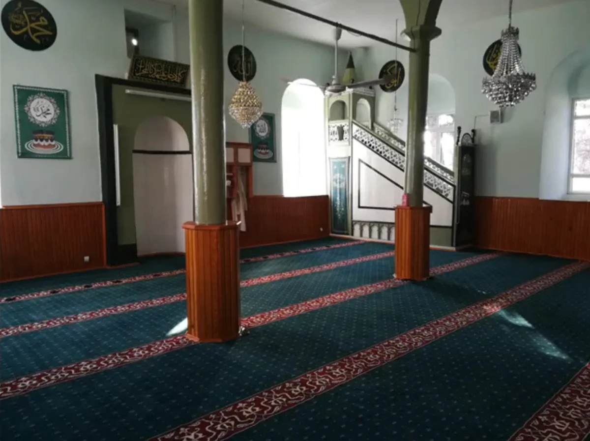 Sofular Mahalle Yukarı Camii'nin iç mekanında yeşil halılar ve İslami hat sanatı detayları.