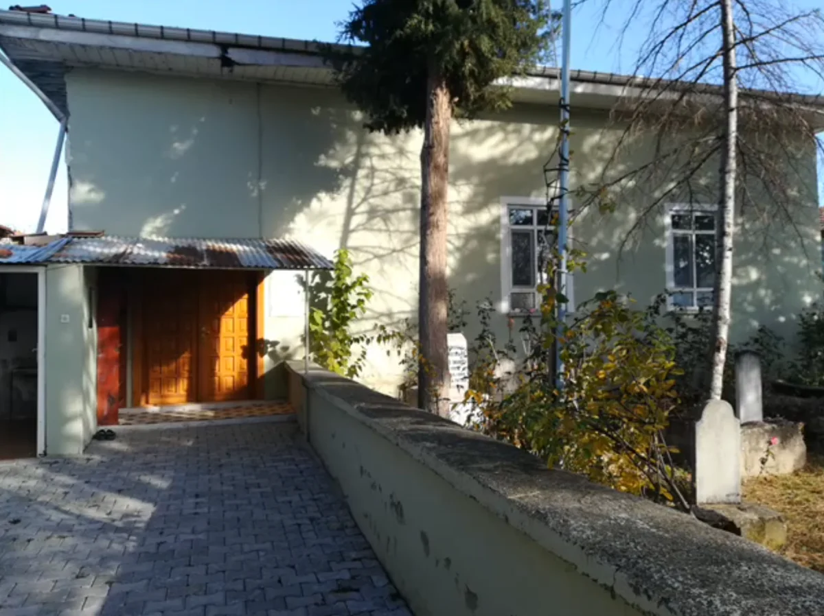 Sofular Mahalle Yukarı Camii'nin ön cephesi, sarı-yeşil duvar rengi ve ahşap kapı.