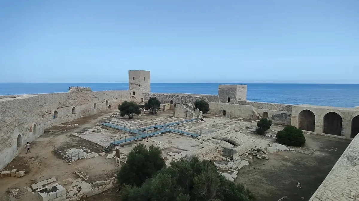Taş kalıntılar, kule ve doğal bitki örtüsü ile çevrili Kız Kalesi manzarası