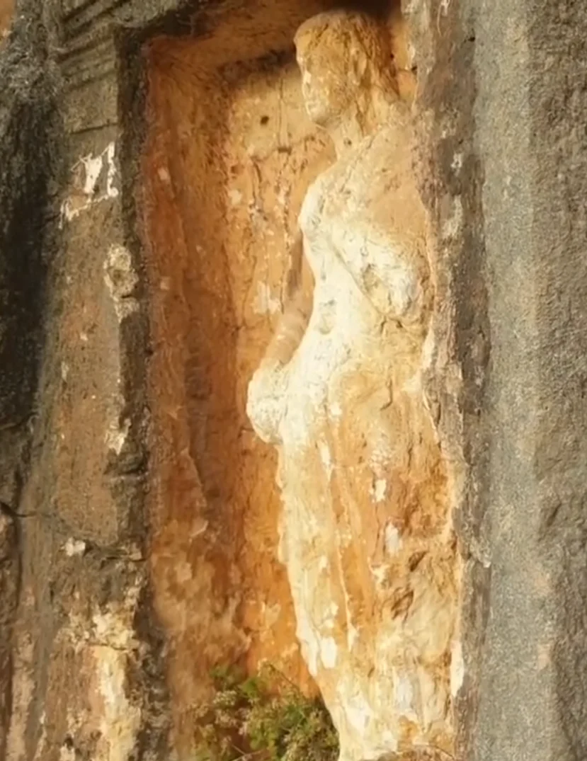 Antik heykel, kaya duvarında belirgin detaylarla yer alıyor.