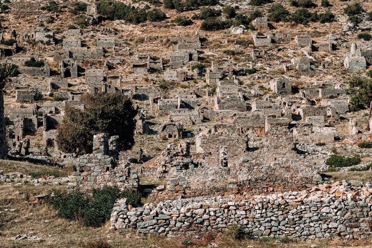 Tepede yer alan harabe yapılar ve çevresindeki yeşil alan.